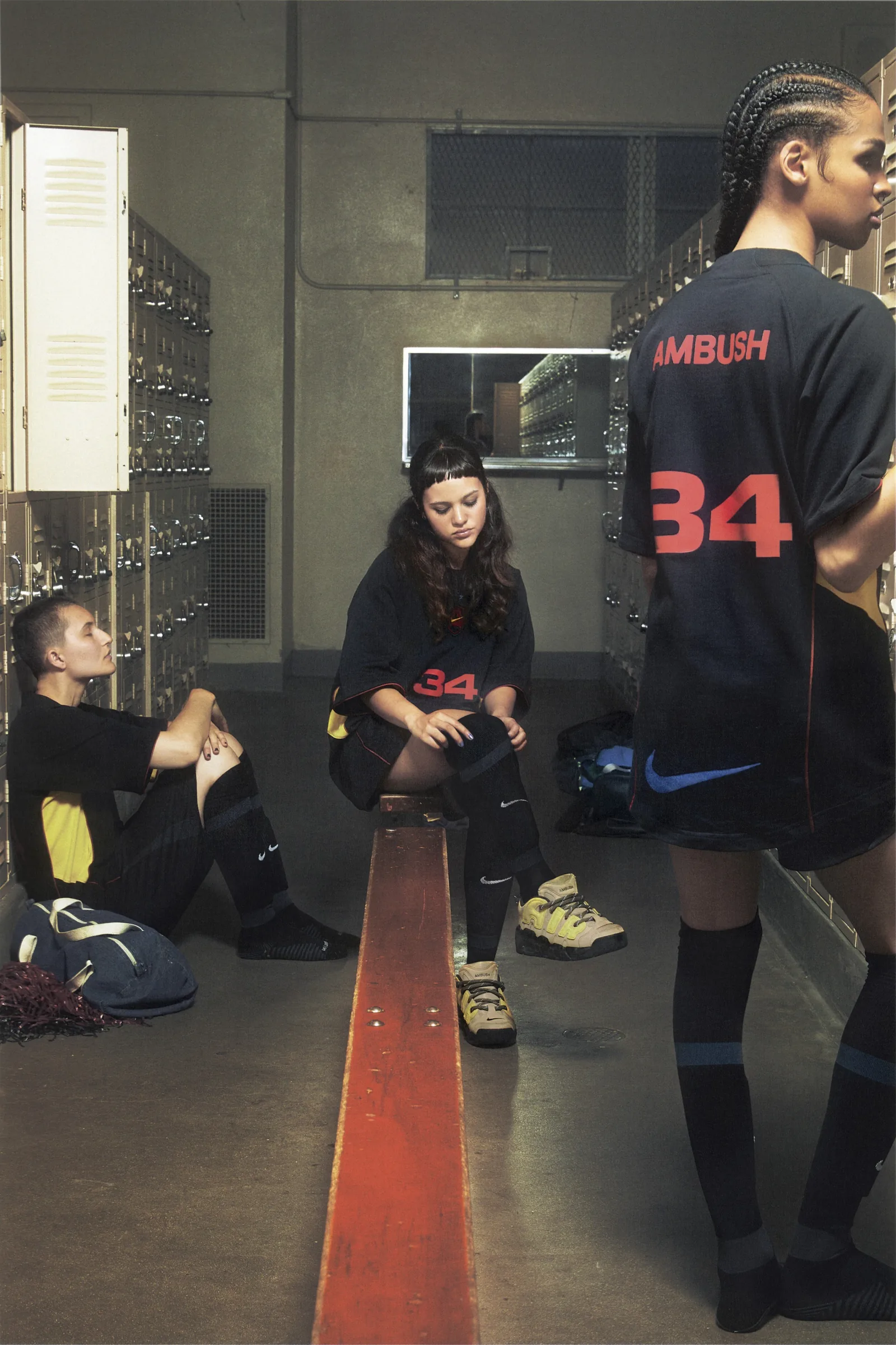 Ba người mẫu mặc áo đấu Nike x AMBUSH trong phòng thay đồ