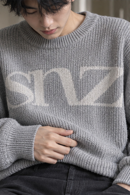 Cận cảnh sweater len xám cho thấy các hàng sợi đan nổi trên bề mặt.