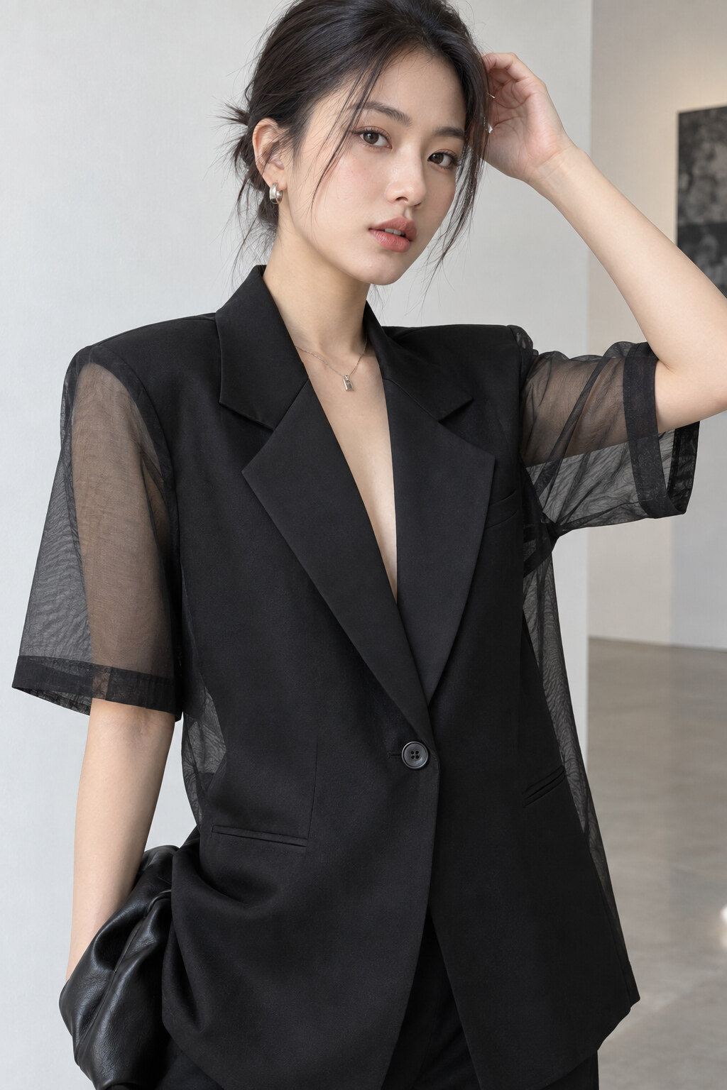 Cận cảnh blazer đen với tay voan trong và thân áo đứng phom.