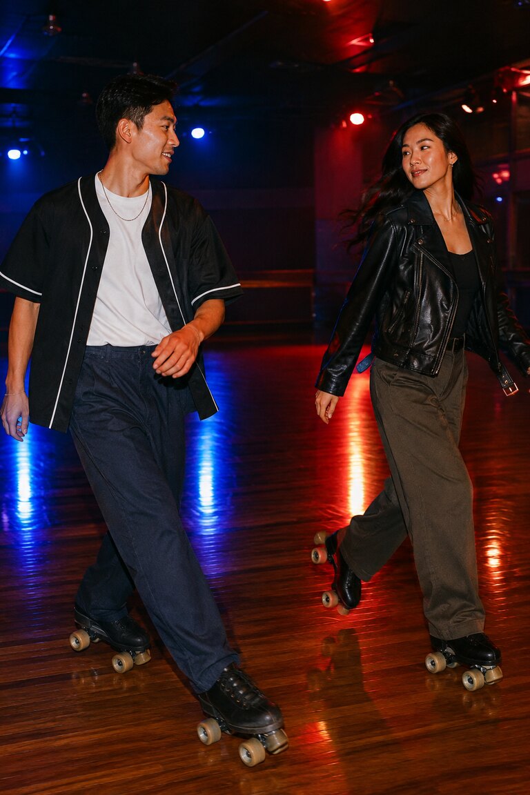 Hai người trượt patin trong áo kiểu baseball và biker jacket dưới đèn đỏ xanh.