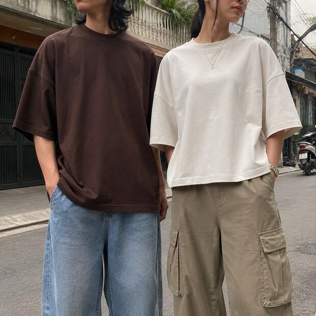 Cận cảnh tỷ lệ thân và gấu áo thun cotton nâu oversized bên áo trắng boxy trên phố.