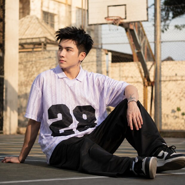 Người mẫu mặc jersey lưới tím nhạt phom rộng số 28 trên sân bóng rổ ngoài trời.