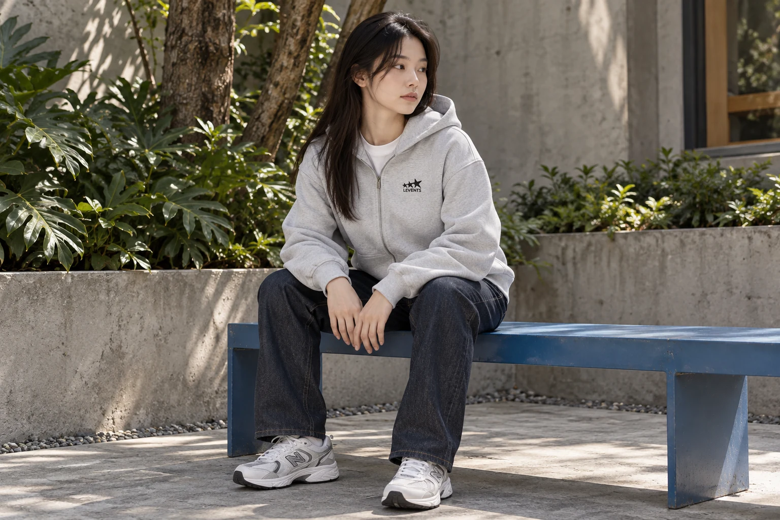 Hoodie xám đi cùng quần jeans và sneaker trong tư thế ngồi.