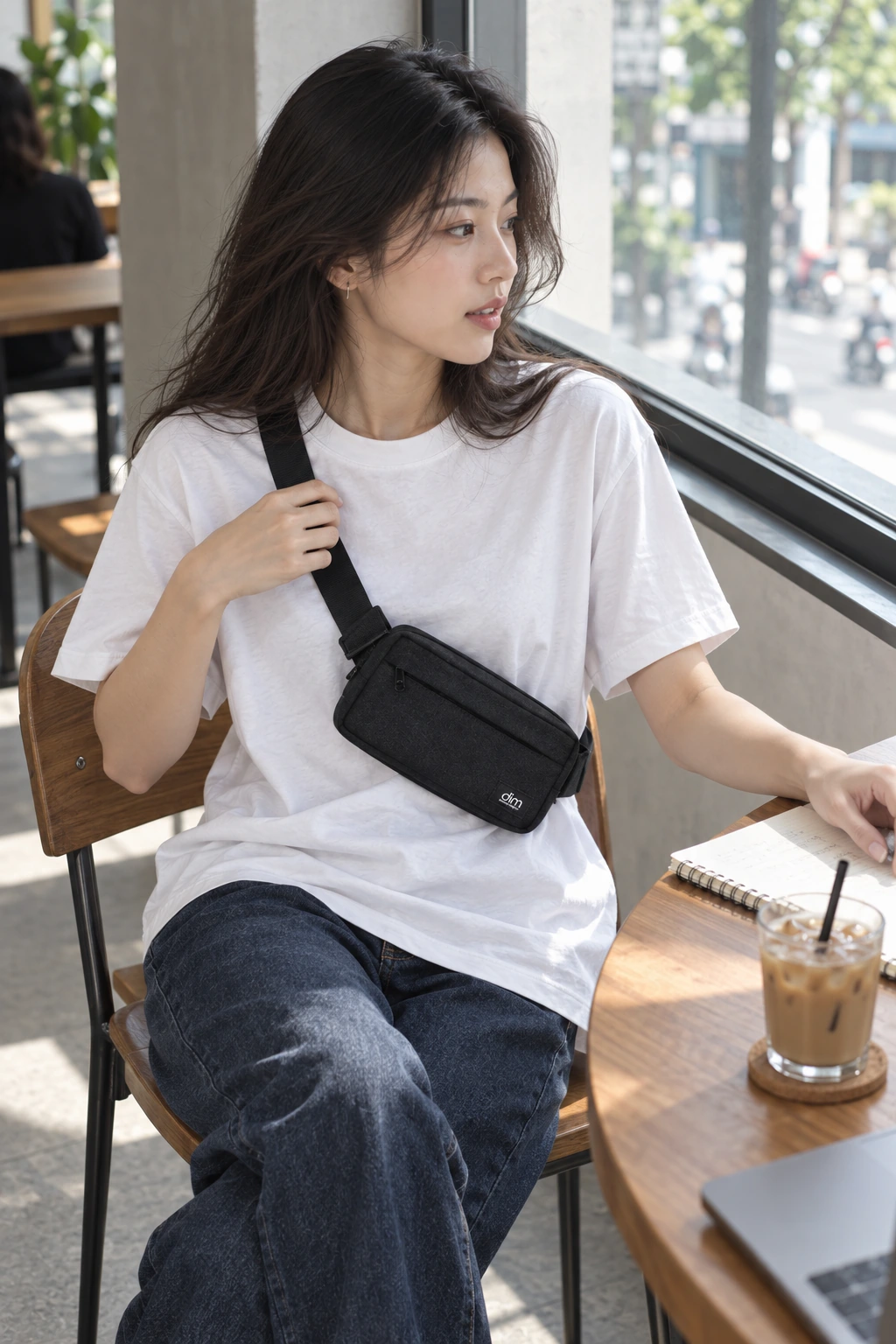 Khi người mặc chỉnh quai, đường chéo đen và thân túi nhỏ hiện rõ trên áo trắng.