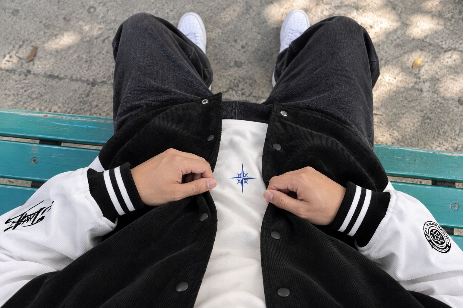Nhìn từ trên xuống, hình in nhỏ trên áo thun nằm gọn giữa hai vạt varsity mở.